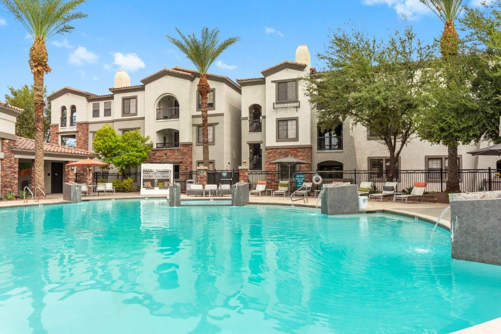 a large swimming pool with palm trees and buildings at CozySuites Glendale by the stadium with pool 28 in Glendale