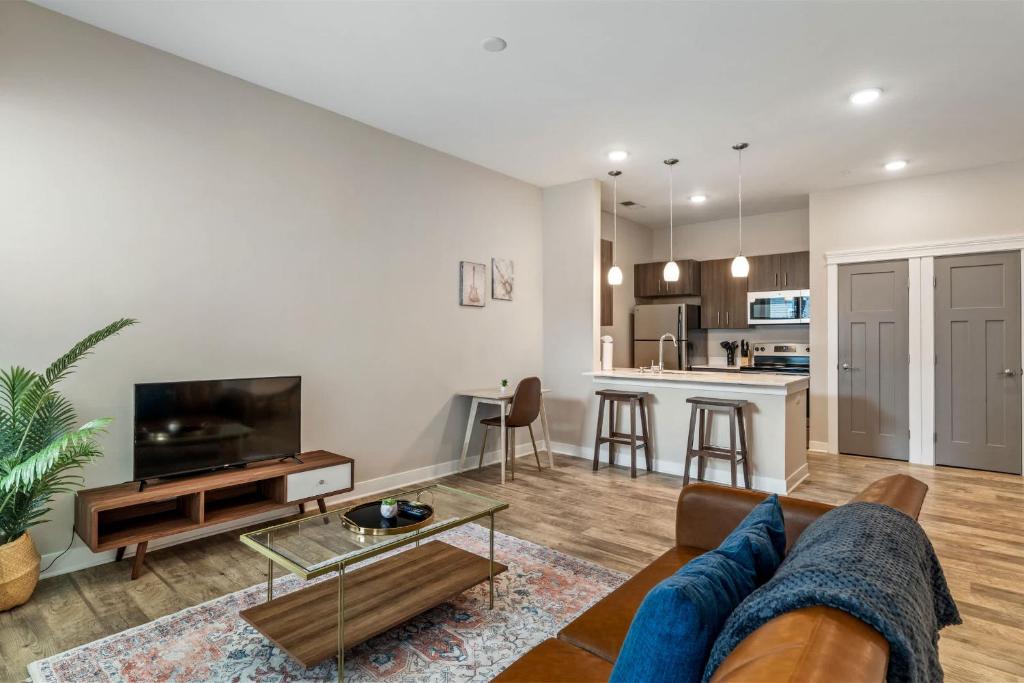 a living room with a couch and a tv and a kitchen at CozySuites - Penrose On Mass with pool and parking #9 in Indianapolis