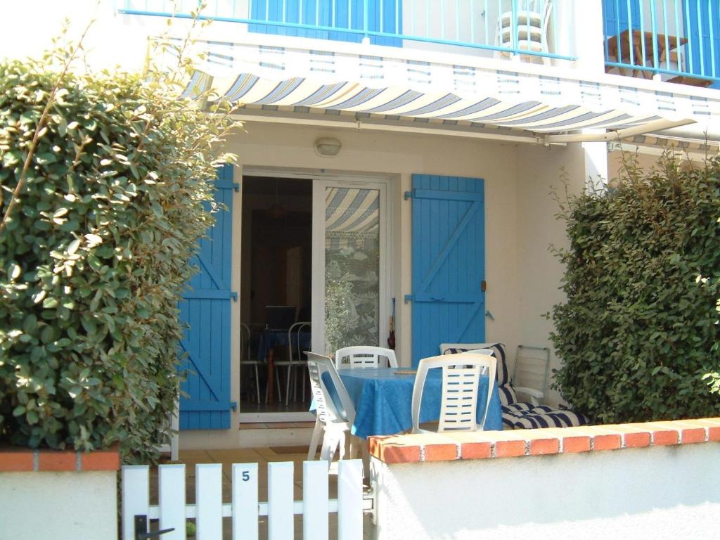 une maison avec des portes et des chaises bleues sur la terrasse couverte dans l'établissement Appartement RDC avec terrasse, à 200m de la plage des Générelles, parking et jardin privé - FR-1-22-229, à La Tranche-sur-Mer