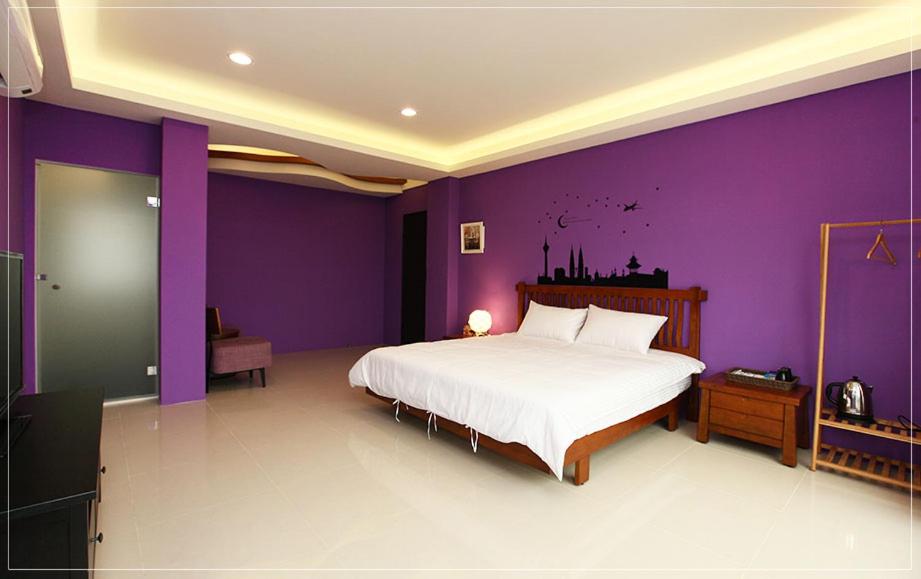 a purple bedroom with a white bed and purple walls at Color Sea B&amp;B in Dawu