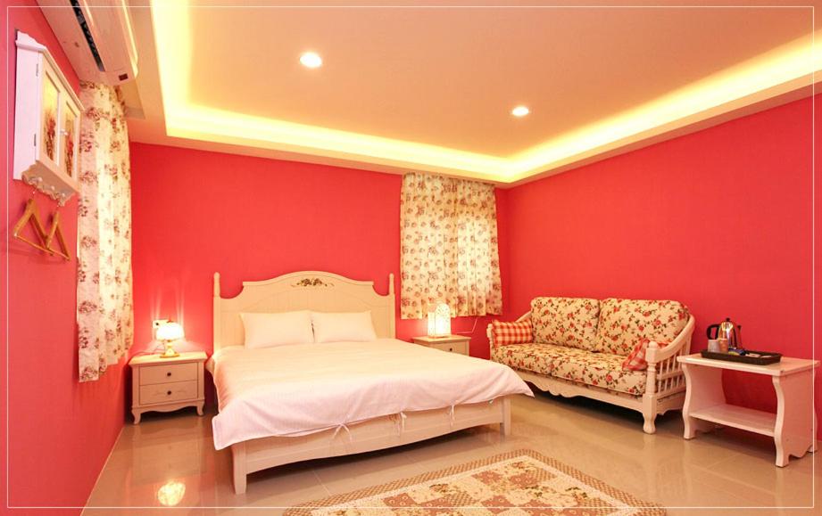 a bedroom with red walls and a bed and a chair at Color Sea B&amp;B in Dawu