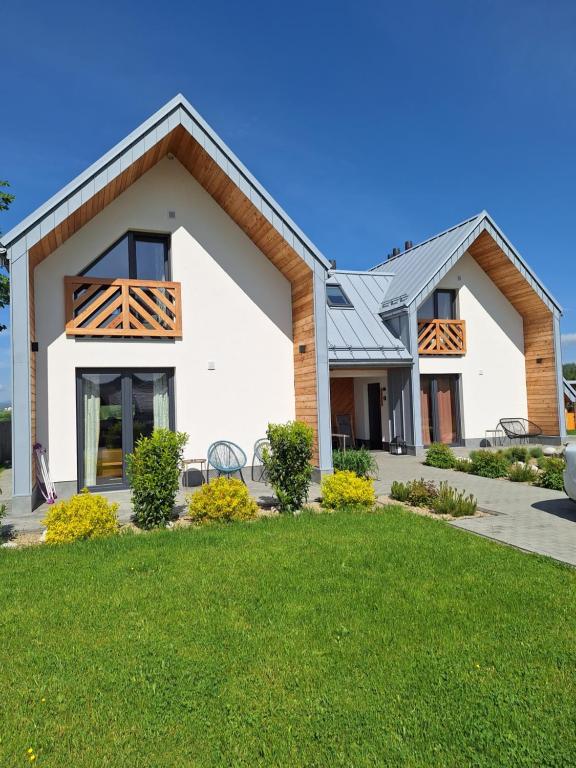 a white house with a metal roof at Domki Szczyt Beztroski - Balia & Sauna in Nowy Targ