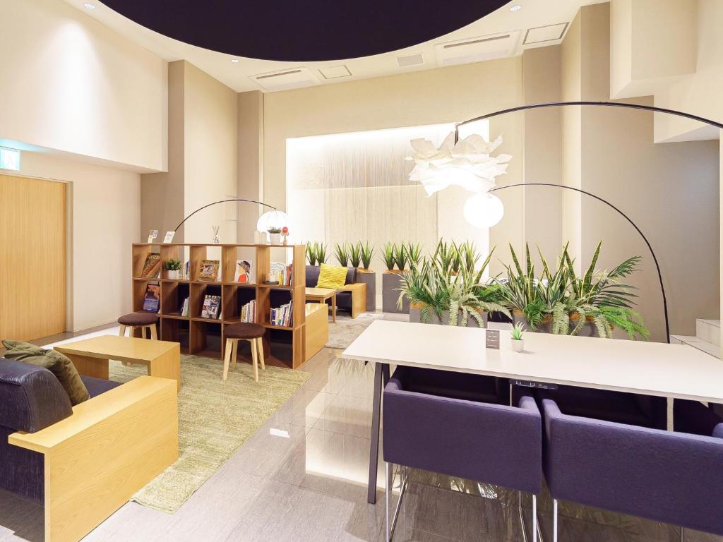 a waiting room with tables and chairs and plants at Sakura Garden Hotel in Osaka
