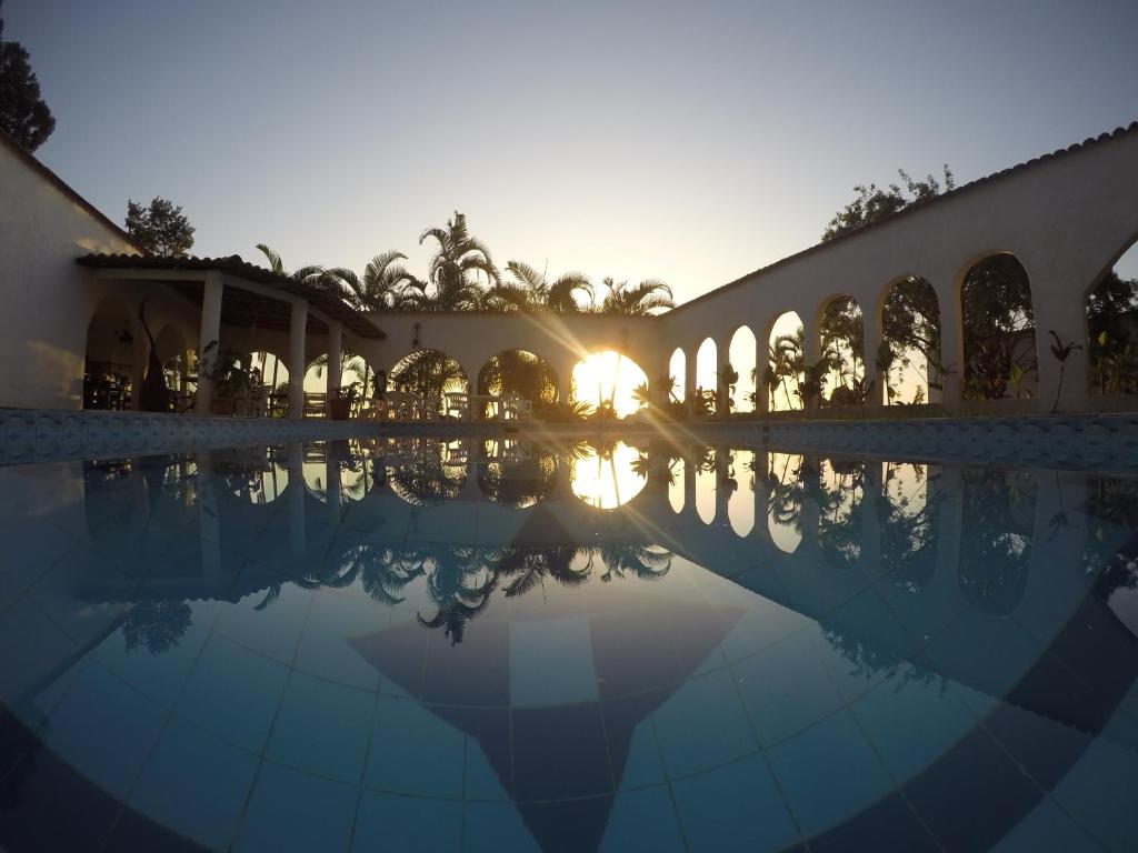 a building with a swimming pool with the sunset in the background at Hostel House 84 in Itajaí