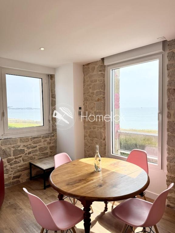 une salle à manger avec une table et des chaises et deux fenêtres dans l'établissement Magnifique appartement vue mer Plage & charme, à Saint-Pierre-Quiberon