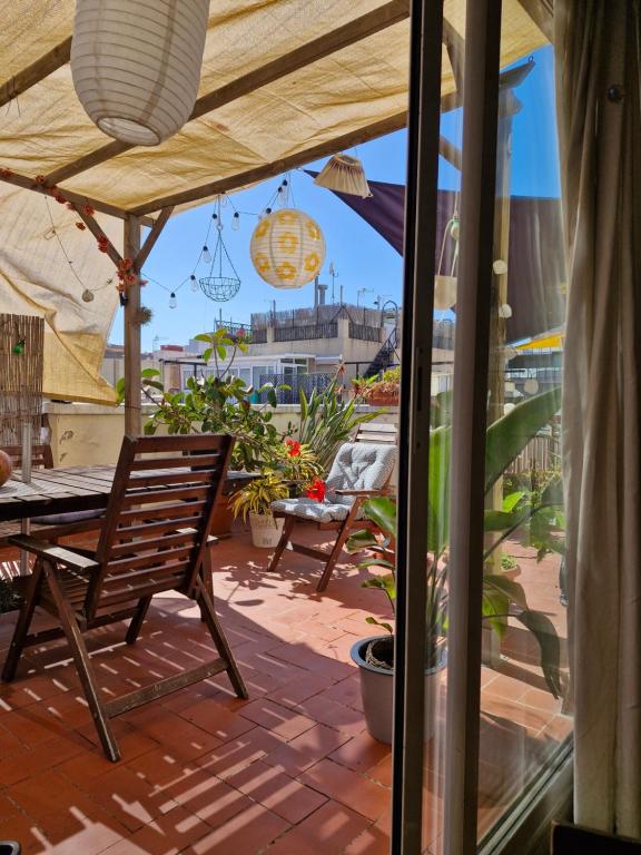 eine Terrasse mit einem Tisch und einem Stuhl unter einem Sonnenschirm in der Unterkunft Atico Soleado in Esplugues de Llobregat