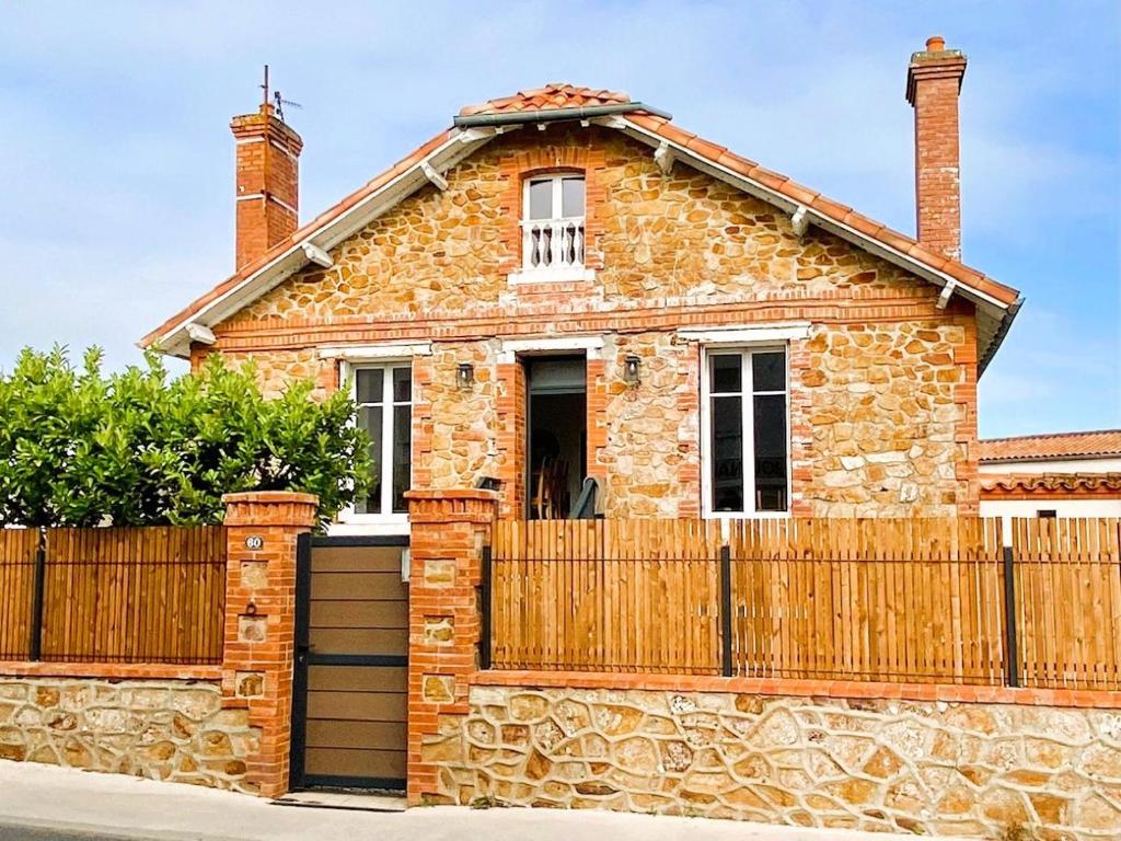 una casa in mattoni con una recinzione in legno di CHEZ MIMI - 6 personnes a Jard-sur-Mer