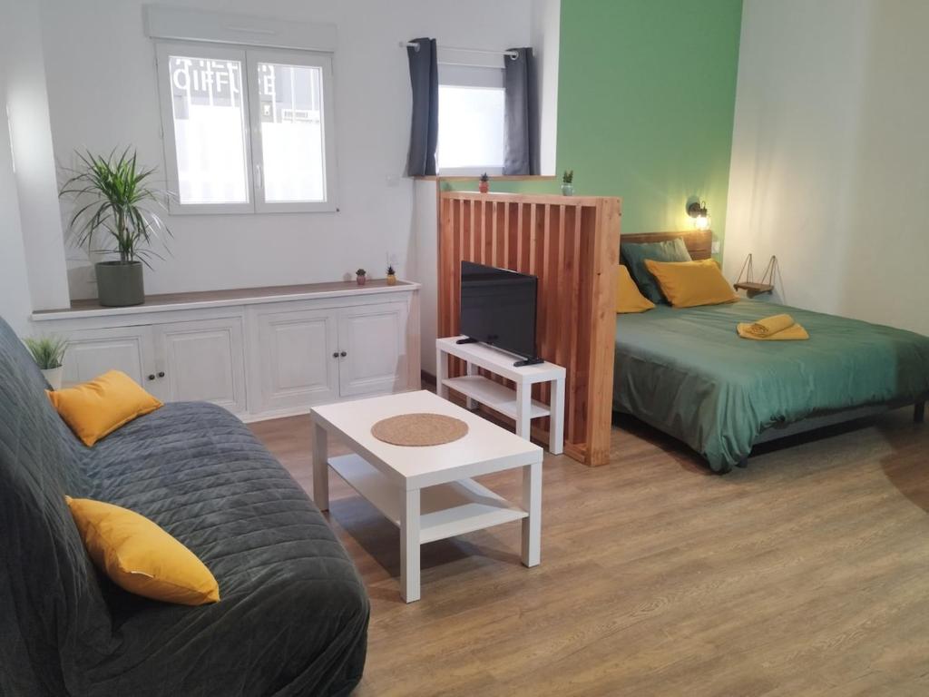 un salon avec un canapé, un lit et une table dans l'établissement Le petit cozy, à La Roche-Chalais