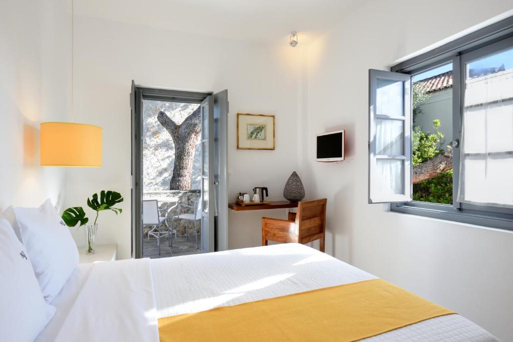 a white bedroom with a bed and a window at Orloff Resort in Spetses