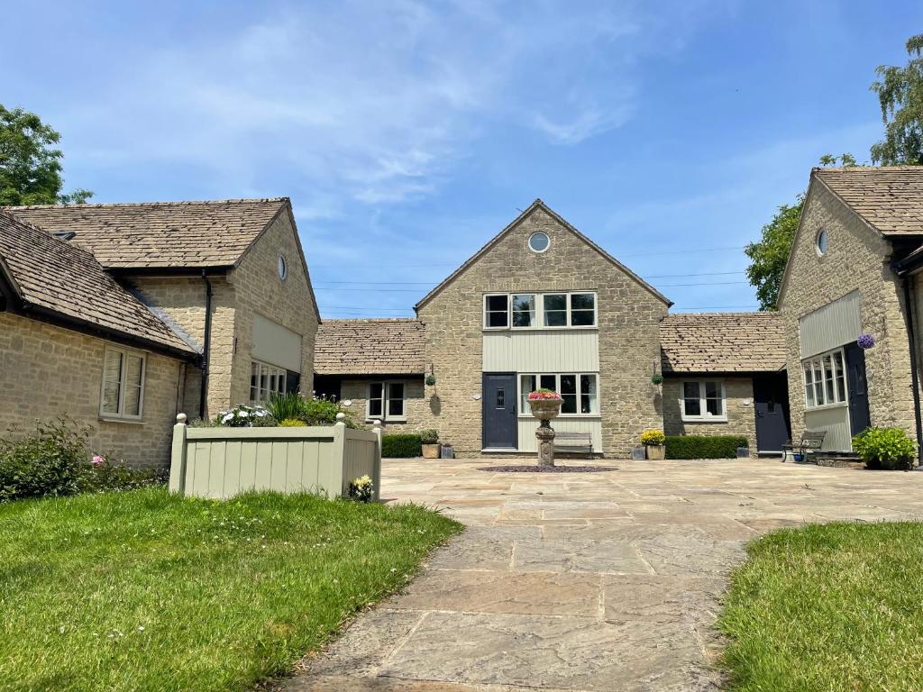 ein großes Backsteinhaus mit Auffahrt in der Unterkunft Windrush Cottage, Seven Springs Cottages in Cheltenham