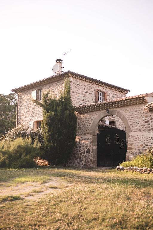 - un grand bâtiment en pierre avec une porte noire dans l'établissement Mediterranean Suite in Ardèche, à Saint-Georges-les-Bains