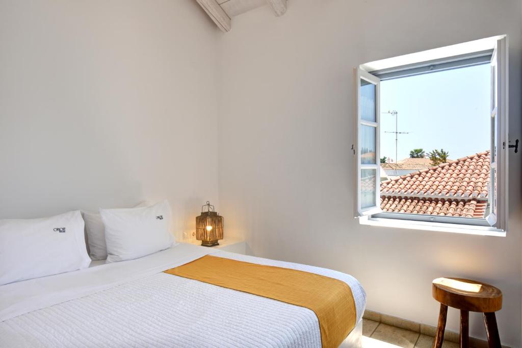 a white bedroom with a bed and a window at Orloff Resort in Spetses