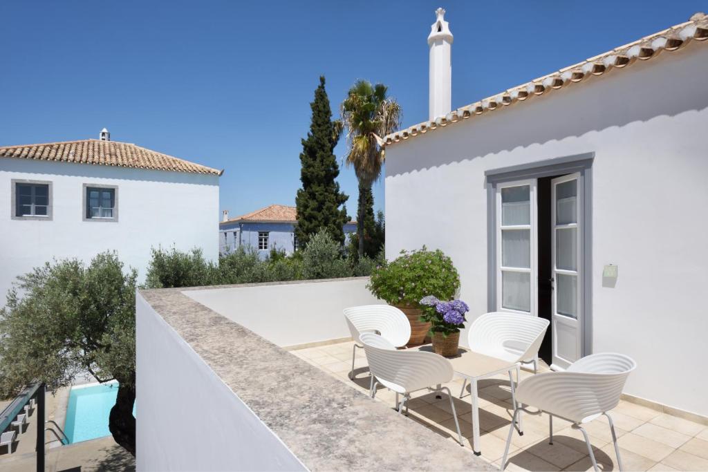 a patio with white chairs and a white house at Orloff Resort in Spetses