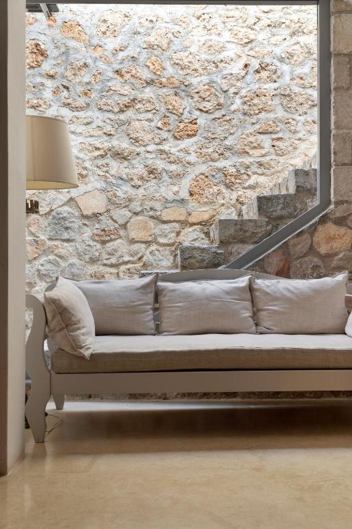 a couch in a room with a stone wall at Orloff Resort in Spetses