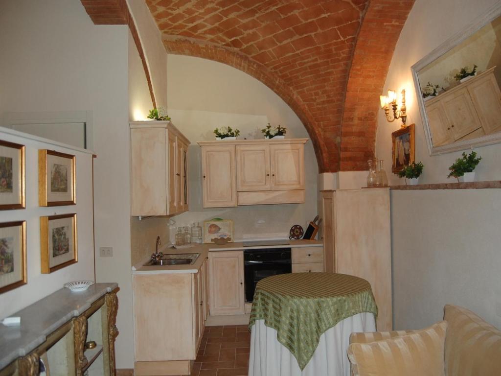 a kitchen with wooden cabinets and a table in it at Monolocale a Buonconvento in Buonconvento