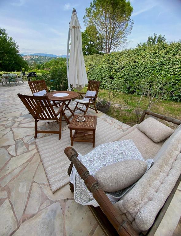 une terrasse avec un canapé, une table et un parasol dans l'établissement Maison spacieuse avec terrasse, terrain clos et lac à proximité, à Fayence