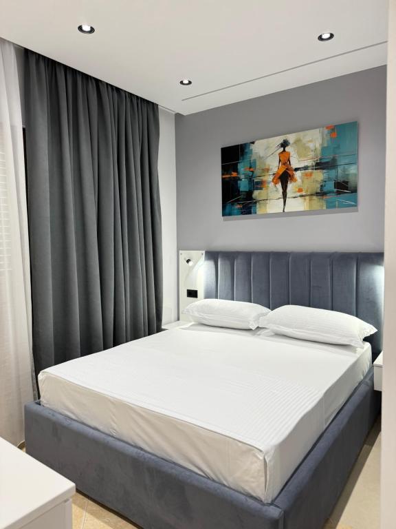a bedroom with a white bed with a painting on the wall at Vila Huqi Seaside in Durrës