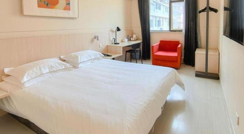 um quarto com uma grande cama branca e uma cadeira vermelha em Jinjiang Inn Xiamen Railway Station em Xiamen