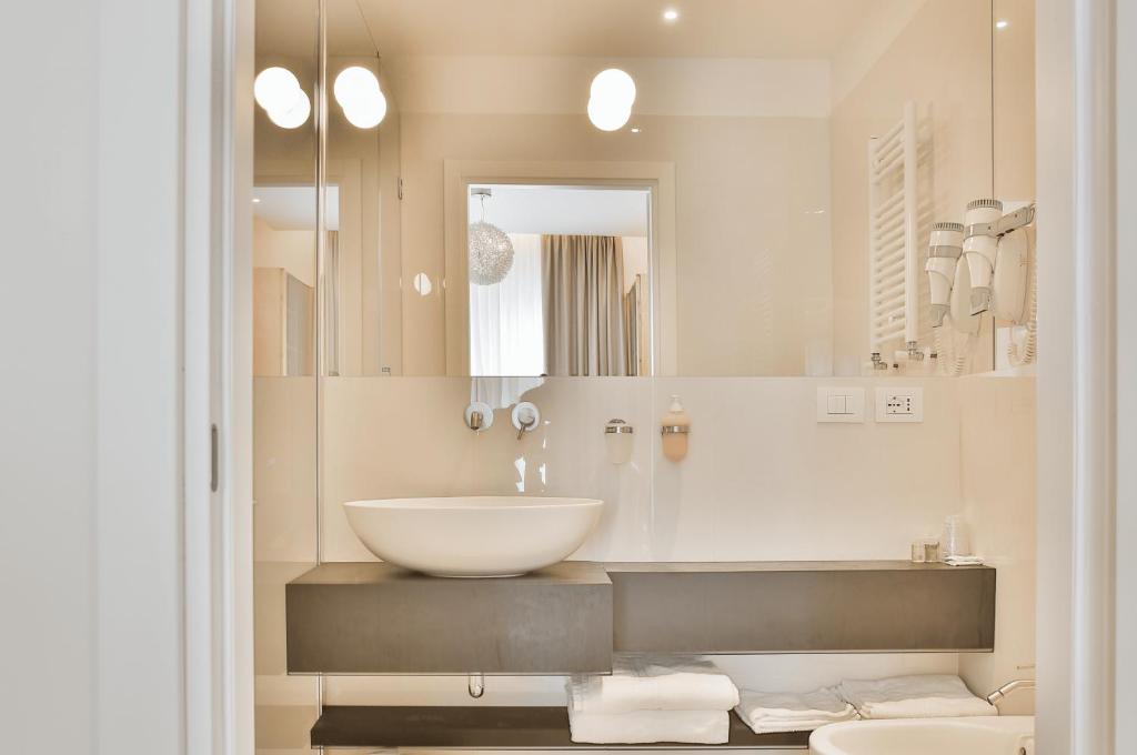 a white bathroom with a sink and a mirror at Hotel Ambassador in Rimini