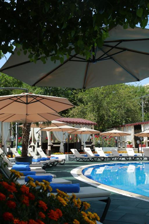 a pool with umbrellas and lounge chairs and a swimming pool at Wyndham Tashkent in Tashkent