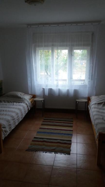 1 dormitorio con 2 camas, ventana y alfombra en Hetedhét Vendégház en Mórahalom