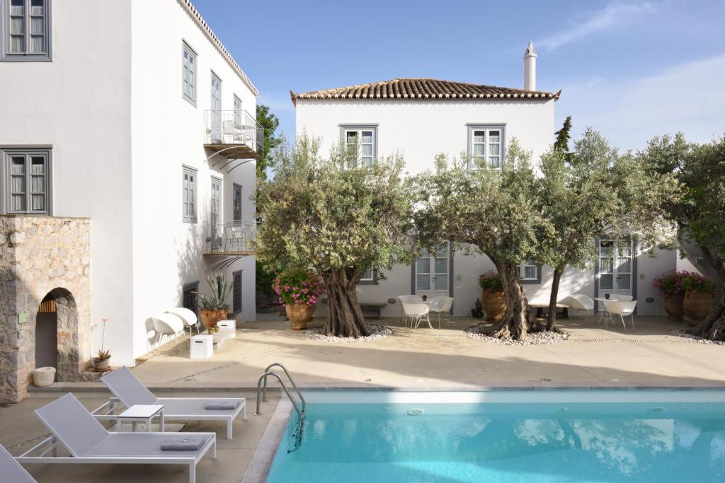 a swimming pool in front of a white building at Orloff Resort in Spetses