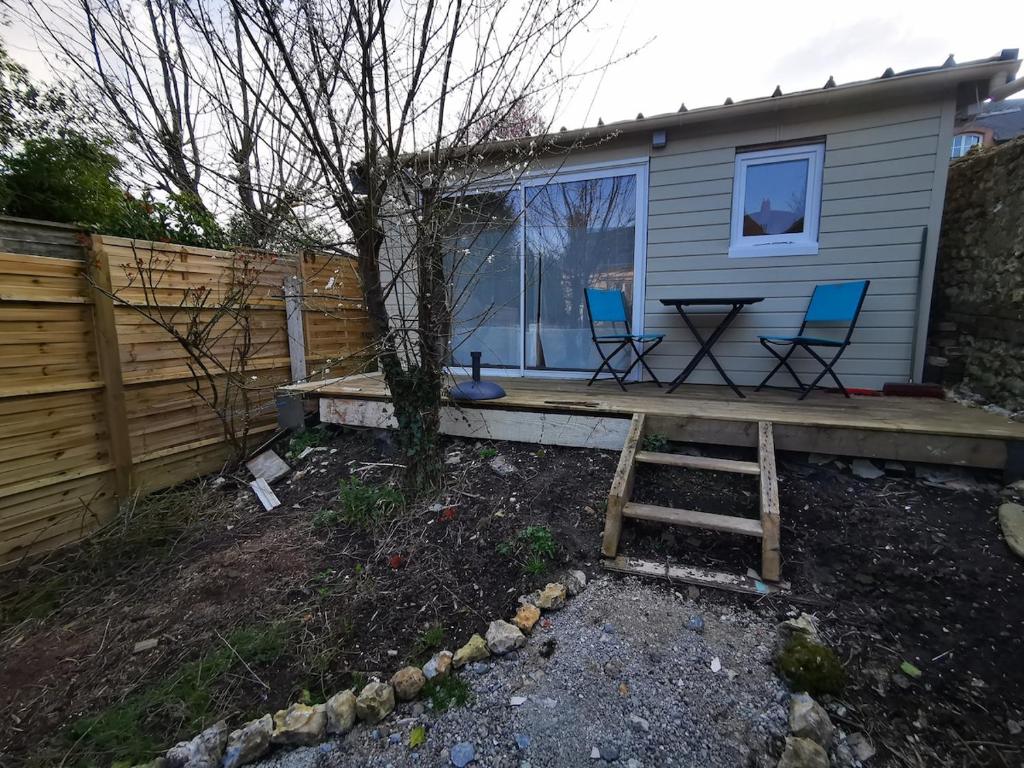 une maison avec 2 chaises et une table sur une terrasse couverte dans l'établissement La petite cabane, à Honfleur