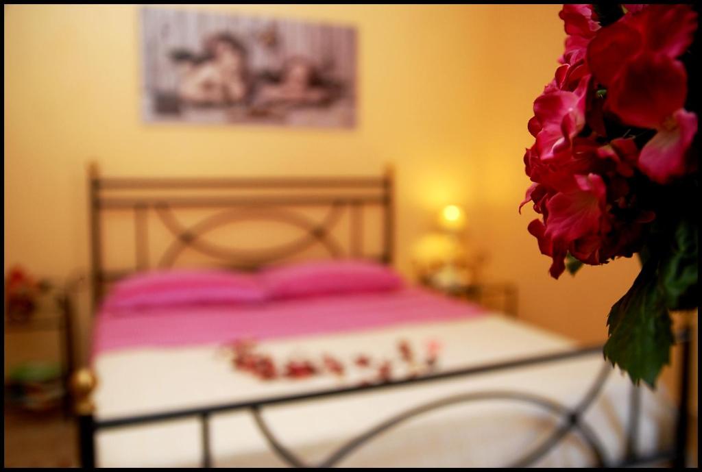 ヴィテルボにあるLa Casina Nel Borgoのピンクの枕と花瓶付きのベッド