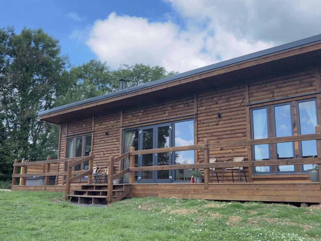 a log cabin with a large deck and windows at Foxglove in Chard