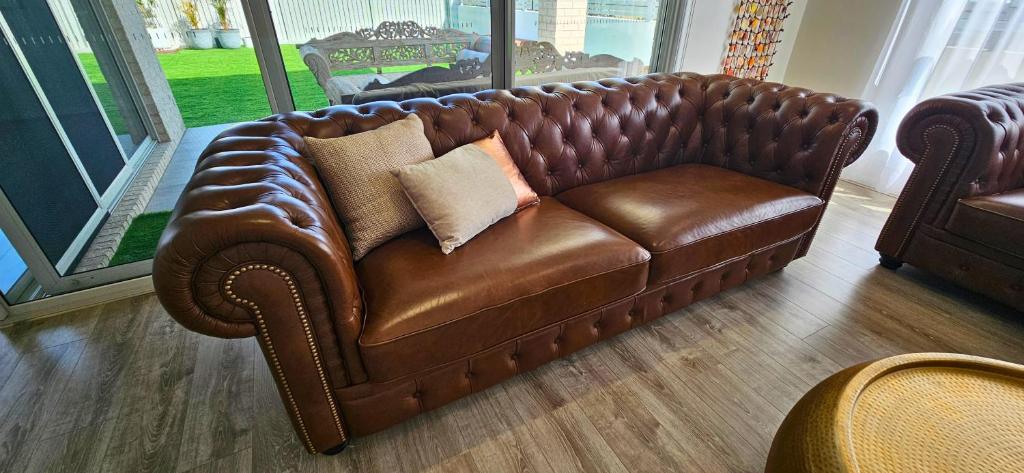 een bruine leren bank met twee kussens erop bij Lotus Grand Home in Mango Hill Sleeps 8 in North Lakes