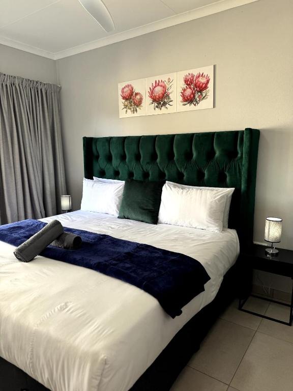 a bedroom with a large bed with a green headboard at Riverhaven Cottage in Muldersdrift