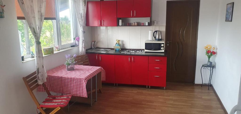 a small kitchen with red cabinets and a table at Casa Geo in Vadu