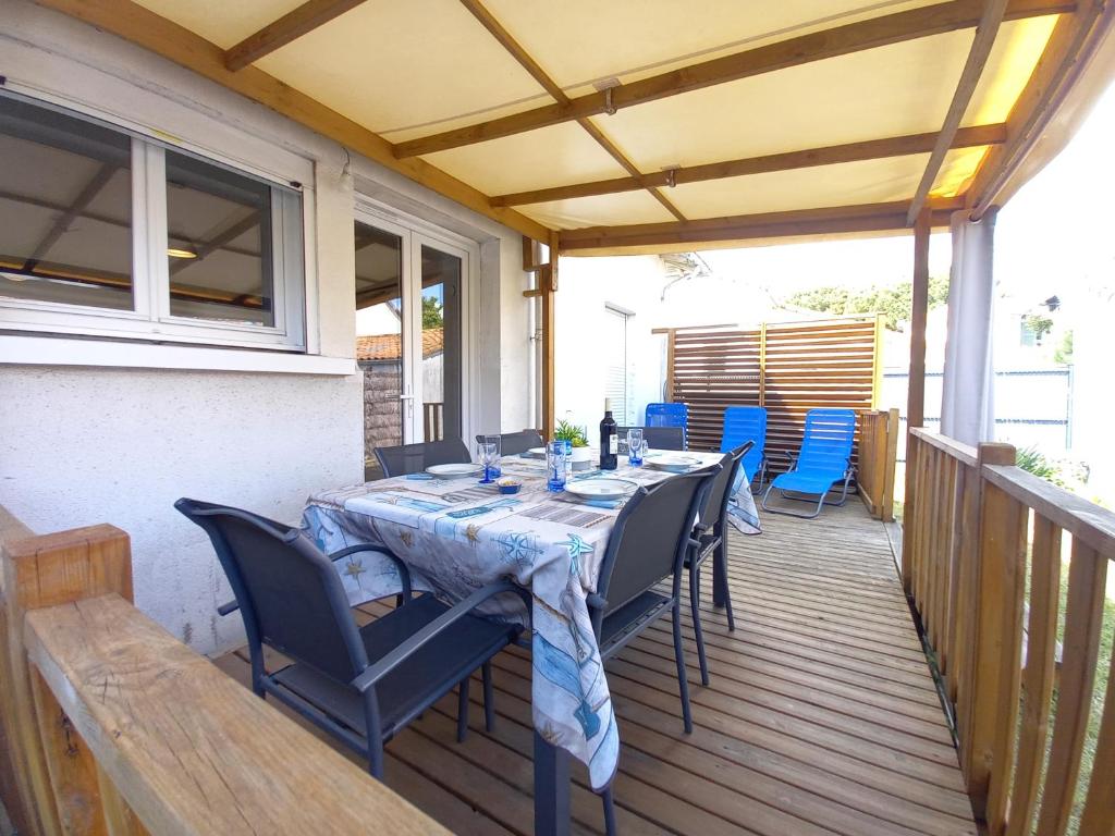 une table à manger sur une terrasse avec des chaises bleues dans l'établissement La Tremblade - MAISON mitoyenne en CENTRE-VILLE - CENTRE et PORT A PROXIMITE, à La Tremblade