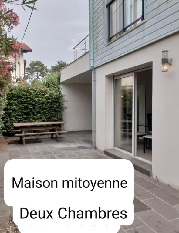 un banc en bois devant une maison avec les mots masonimeters dywk dans l'établissement Maison 2 Chambres, à Mimizan-Plage