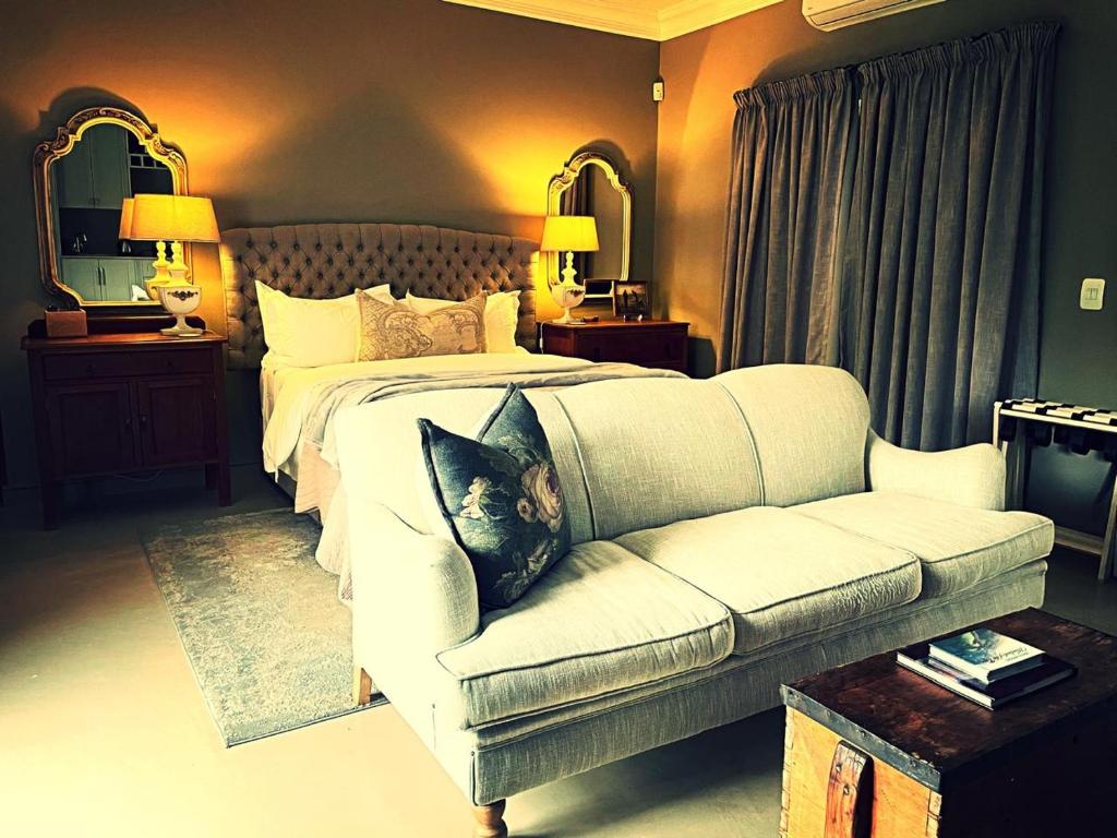 a bedroom with a white bed and a couch at Belle Vallee Guestroom 1 in Wellington