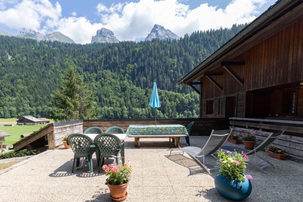 un patio avec des chaises, une table et un parasol dans l'établissement Les Gentianes, au Grand-Bornand