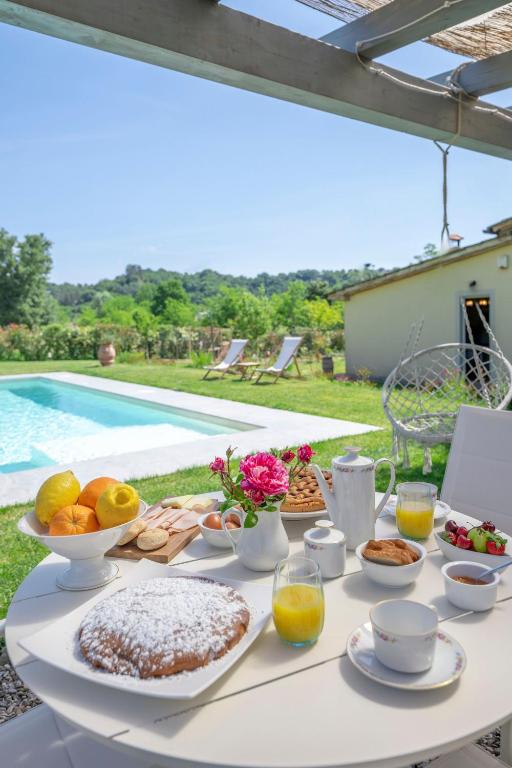 - une table blanche avec de la nourriture et des boissons à côté de la piscine dans l'établissement Il Fienile Toscano, à Montevarchi