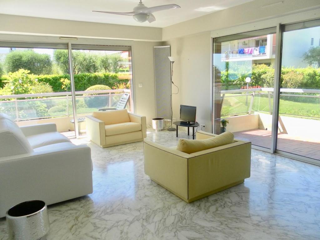 - un salon avec des canapés blancs et une grande fenêtre dans l'établissement 2 pièces nice terrasse cosy, à Nice