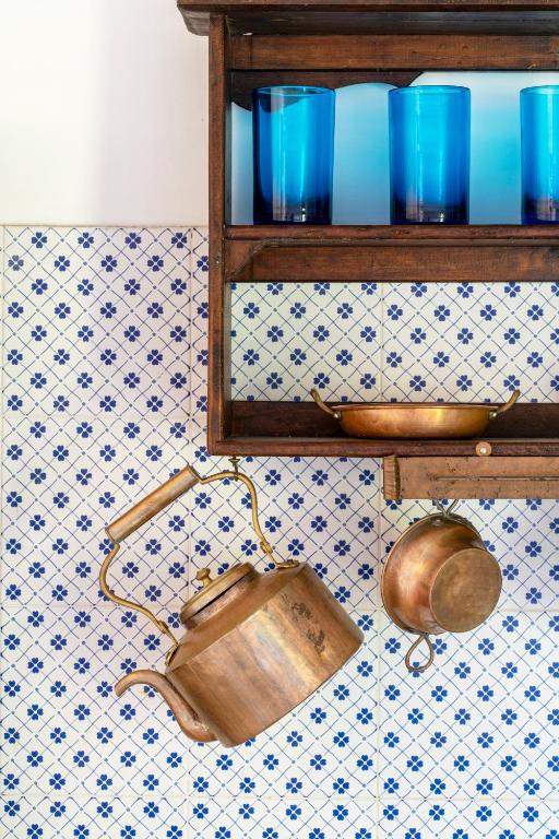 a shelf with blue glasses and a pot on a wall at Nel borgo i gatti di Monet in Castelnuovo di Porto