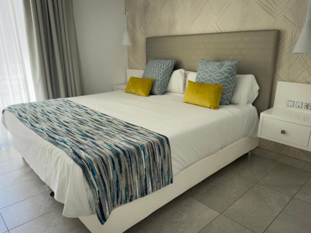 a bedroom with a large bed with yellow and blue pillows at Holiday Club Playa Amadores in Amadores