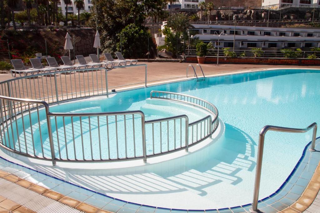 a blue swimming pool with stairs in a building at Holiday Club Playa Amadores in Amadores