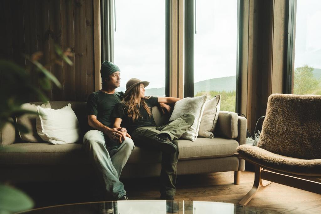 a man and woman sitting on a couch looking out a window at Exclusive Suite in the Sunnmøre Alps, Near Geiranger & Hjørundfjord in Stranda