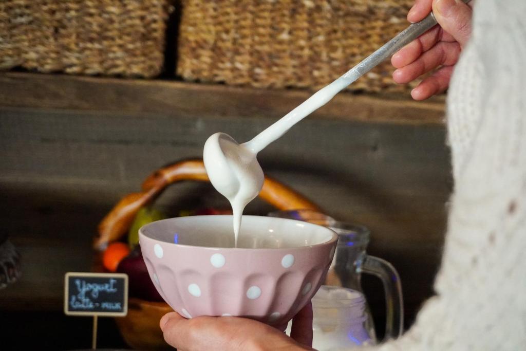 a person holding a spoon and a cup of milk at Hotel Edelweiss in Limone Piemonte