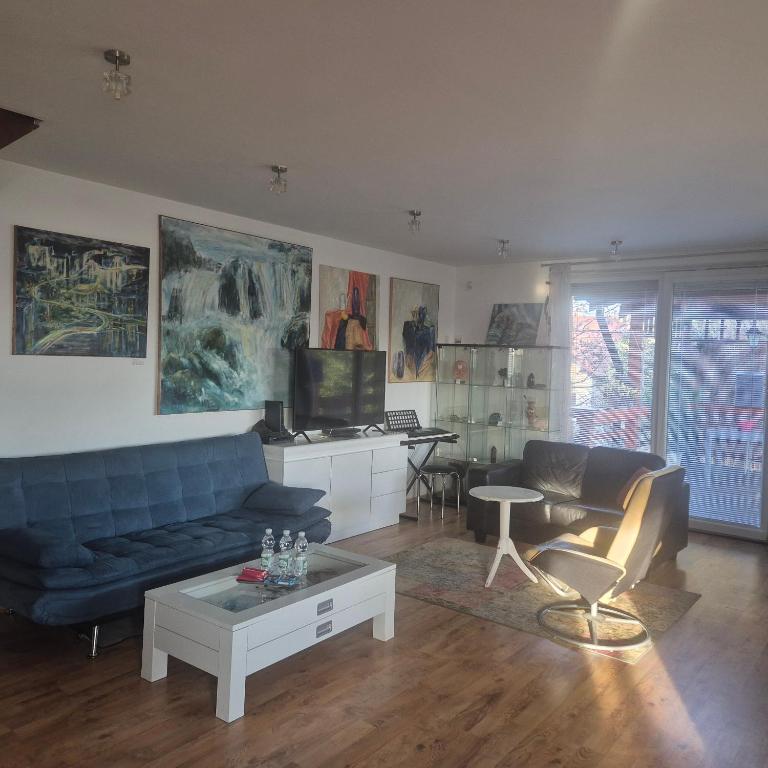 a living room with a blue couch and a table at Living in the Gallery in Jánošíková