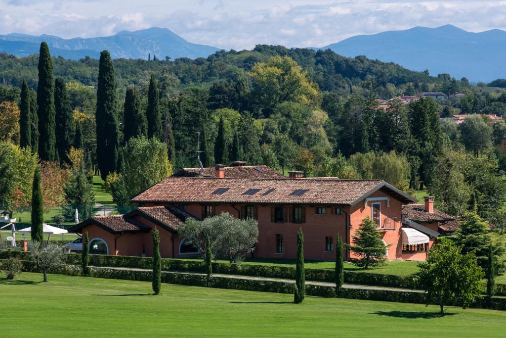 a house in a field with trees and mountains in the background at La Tavernetta Al Castello in Capriva del Friuli