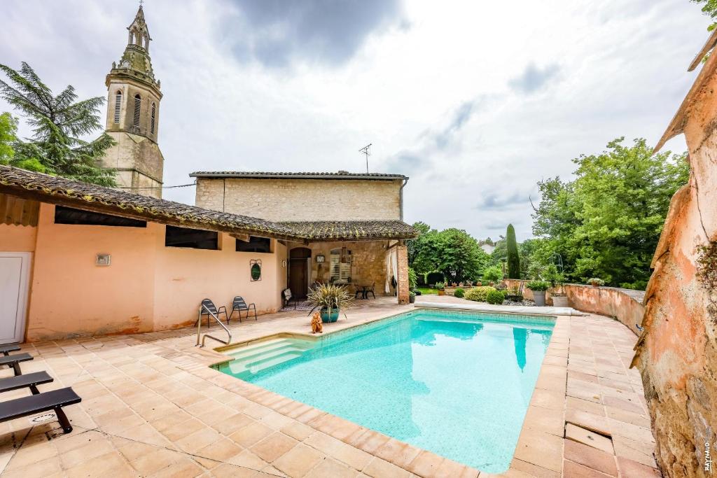 an old house with a swimming pool and a church at Le Refuge de la Brêche in Cahuzac-sur-Vère