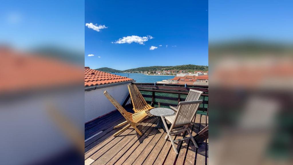 a deck with chairs and a table and a view of the water at Voltera Apartments in Betina Old Town, with Parking Nearby in Betina