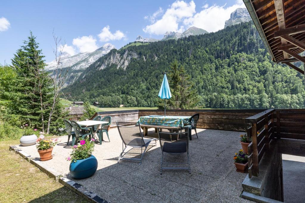 d'une terrasse avec une table, des chaises et des montagnes. dans l'établissement L'Hysope, au Grand-Bornand