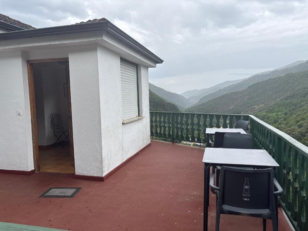 un balcone con tavoli e sedie con vista sulle montagne sullo sfondo di Hotel rural casa Ferreiro a Seoane
