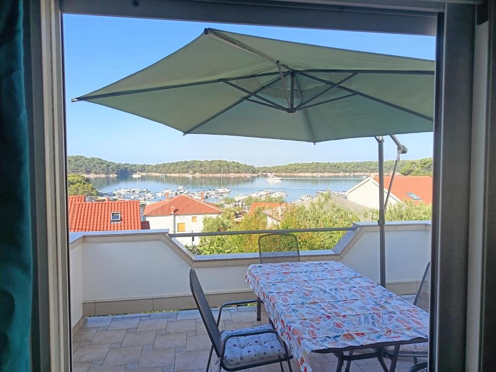a table and chairs on a balcony with an umbrella at APARTMAN I SOBE MARIJANA in Rab
